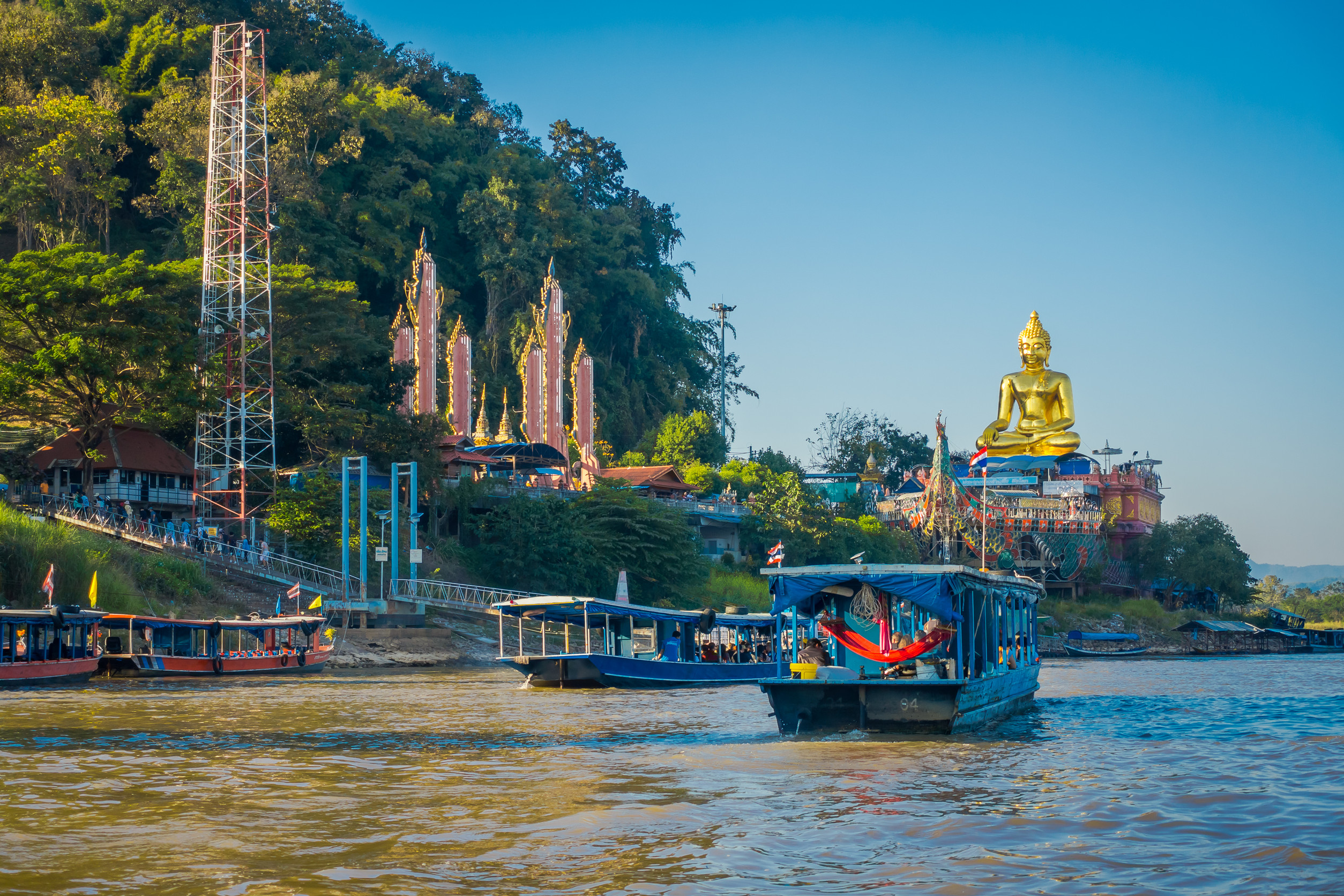 beautiful outdoor view of a group of tourists in tourist boats visiting the golden budha located